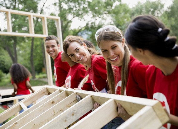 A group of people lifting a wood frame