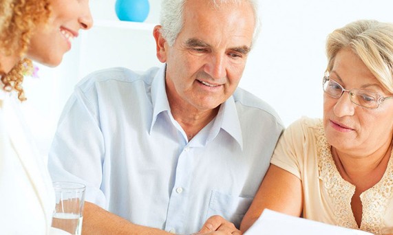 A woman talking to two elderly people  